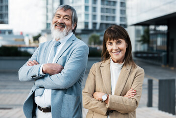 Business people, senior and urban portrait with man and woman smile, diversity and team in company motivation cityscape. Corporate, mature and professional outdoor with confidence and pride in city.