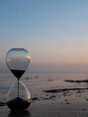 Sand hourglass at the beach at sunset - obrazy, fototapety, plakaty