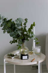 Stone table and vase with eucalyptus and spruce. Candles for relaxing in the room.