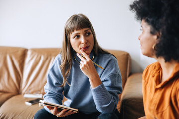 Two young business women having a discussion in an office lobby