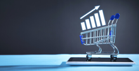 Shopping cart, tablet and growth graph. Increase in sales