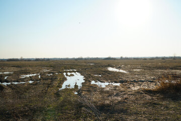 Puddles on a dirt road and a wild field during the autumn or spring thaw. Autumn or spring off-road