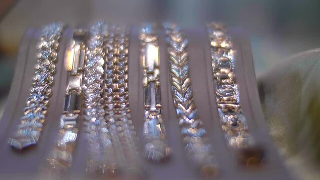 Collection of beautiful expensive fashionable gold braceletes with incrustation of gems behind the glass of a jewelry store showcase shine brightly with their diamonds and surfaces. Close up