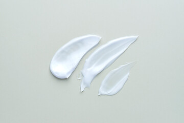 White cosmetic cream lotion moisturizer strokes on grey background. Hygiene, skincare product...