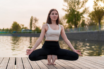 Fototapeta na wymiar Young woman doing yoga by the lake