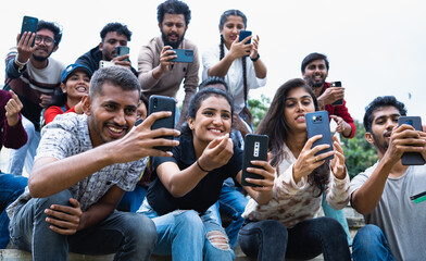 Group of audience or crowd taking photos of a player at stadium on mobile phone - concept of...