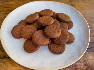 Cacao biscuits in white plate on wooden background