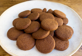 Cacao biscuits in white plate on wooden background