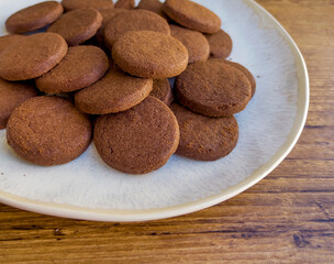 Cacao biscuits in white plate on wooden background