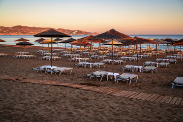 Empty beach with sunshade and deckchair in nice sunrise warm illumination. Amoudara, Crete. - 544820146