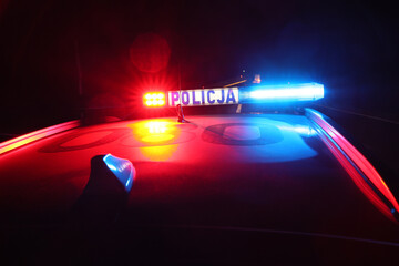 Nocna interwencja alarmowa policji - Sygnalizator błyskowy niebieski na dachu radiowozu policji polskiej w nocy. © FotoDax