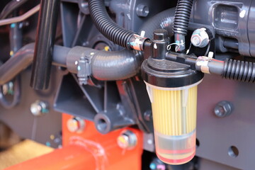 Tractor fuel filter. Transparent fuel filter with black rubber hose mounted on tractor side with copy space. Selective focus - obrazy, fototapety, plakaty