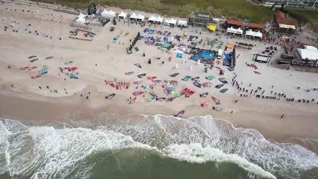 Big windsurfing event in Germany, Sylt. Top down aerial view of windsurf world cup. Water sports competition on the North Sea coast. Busy German coastline captured by drone in 4K.