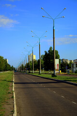 Road with lanterns and green spaces under blue sky	
