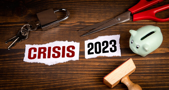 Crisis and 2023 development concept. Cut piece of paper on a wooden table