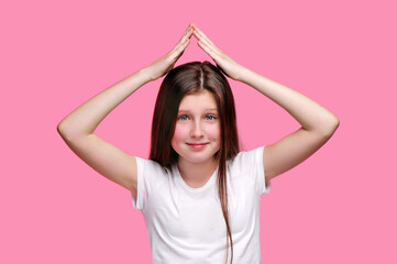 Smiling teen girl making roof upon her head with hands