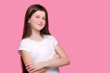 Smiling teen girl with crossed hands against pink background