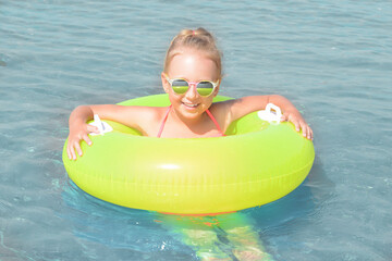 Happy little girl with inflatable ring in sea on sunny day