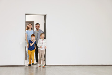 Happy family entering in their new apartment on moving day. Space for text
