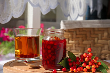 Tasty hot drink, jam and viburnum berries on wooden board indoors
