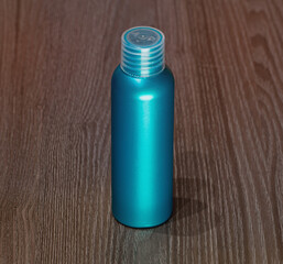 A green plastic bottle for detergent, tonic, conditioner, soap and shampoo on a wooden table. Natural organic cosmetics, packaging with an empty label.
