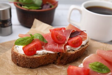 Tasty bruschetta with prosciutto, tomatoes and cheese on white wooden table, closeup