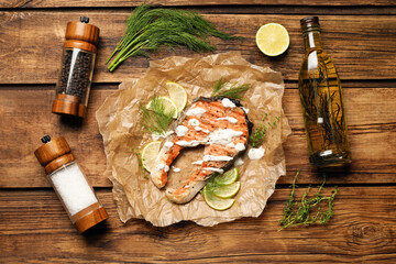 Tasty salmon steak with sauce, spices and oil on wooden table, flat lay