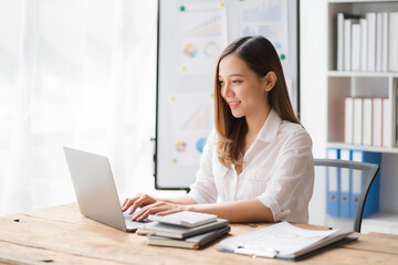 Charming asian businesswoman sitting working on laptop in office.