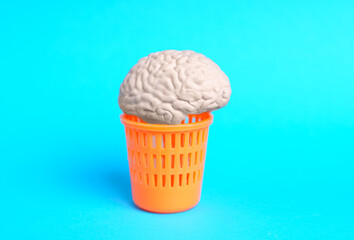 Human brain in a trash can on blue