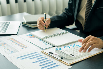 business office concept At her desk, a female accountant presses a calculator for a monthly financial report or company profit.