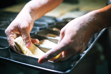 Flour-filled hands filling loaf pans. Homemade bread. Buy local. Traditional preparation. Handmade. Bakery shop. Hands working dough close up.