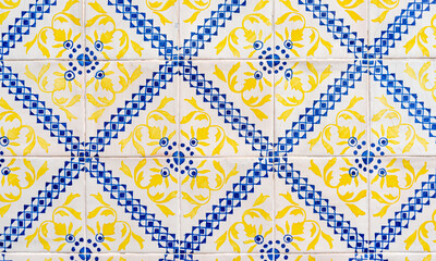 Fragment of building wall with yellow and blue ceramic wall tiles Azulejo Abstract decorative background textured ornate pattern. Traditional ornate Portuguese architecture 