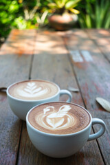 Latte art coffee with swan and heart tree shape in coffee cup on wooden background, Hot drink
