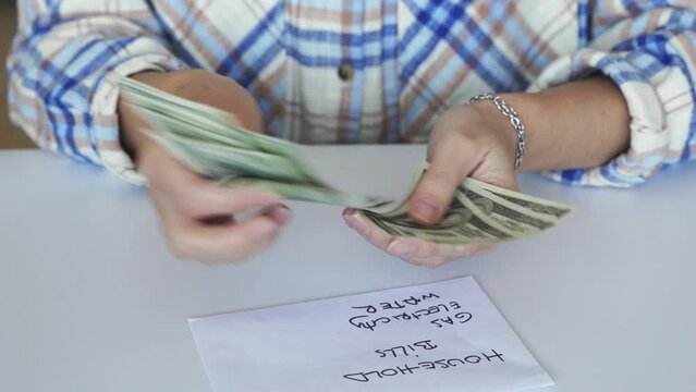Close up female hand counting dollars money. Family domestic planning household expenses budget. Economy crisis, gas fee price increasing. Life cost raising. Putting money to envelope to save.