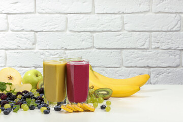 Fresh colorful fruit smoothies and ingredients on table against white brick wall. Space for text - obrazy, fototapety, plakaty