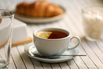Cup of aromatic tea with lemon on table, closeup