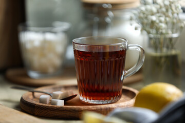 Glass cup with delicious tea and sugar on table, closeup