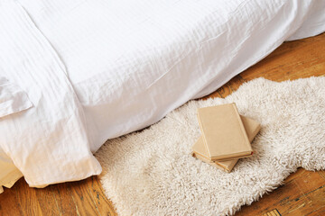 Bedroom interior design. Inflatable mattress with bedding on a wooden floor, next to it there is a rug with a stack of books