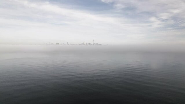 Toronto's Skyline in the distance as viewed from a drone flying over a foggy lake, Toronto, Canada captured by Anthony Saleh