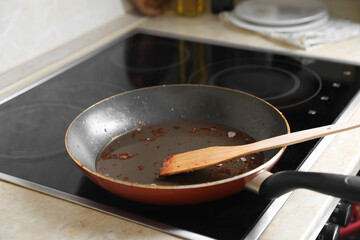 Frying pan with spatula and used cooking oil on stove