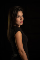 Naklejka premium Portrait of a young woman on a black background with a soft, warm and cozy light.