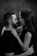 Portrait of a loving couple looking into each other's eyes in black and white on a black background with smoke.