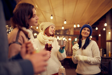 Group of young people spending time together, drinking mulled wine, talking, laughing at winter...