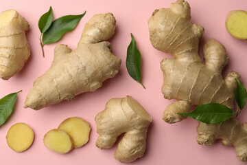 Fresh ginger with green leaves on pale pink background, flat lay
