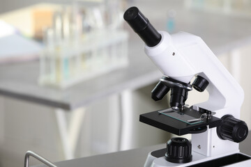 Modern medical microscope on metal table in laboratory, space for text