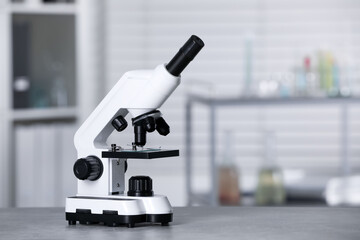 Modern medical microscope on grey table in laboratory, space for text