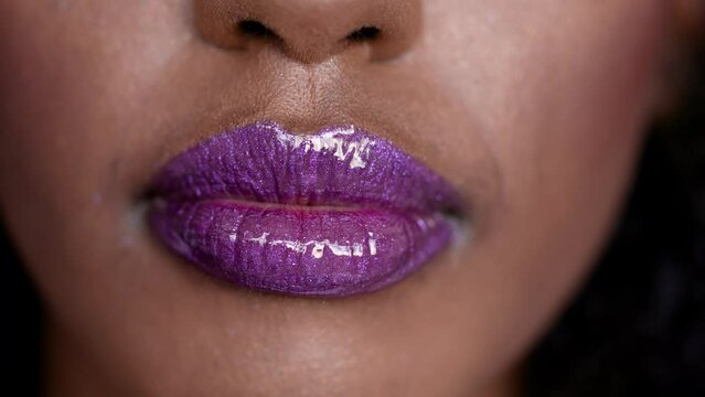 Close up shot on purple glowing wet makup lips of beautiful African fashion model