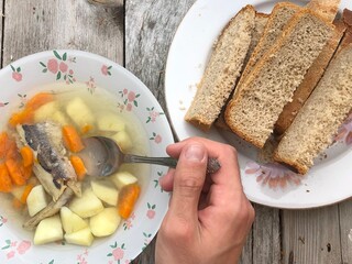 Fish soup and bread served on a wooden table, healthy traditional food concept, top view.