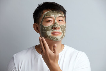 Asian Man Face Mask. Closeup Of Healthy Handsome Male Applying Green Clay Mask On Face. Spa...