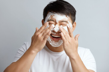 Man Face Skin Care. Asian Male Cleaning Facial Skin with Foam Soap. Happy Guy Cleansing Face...